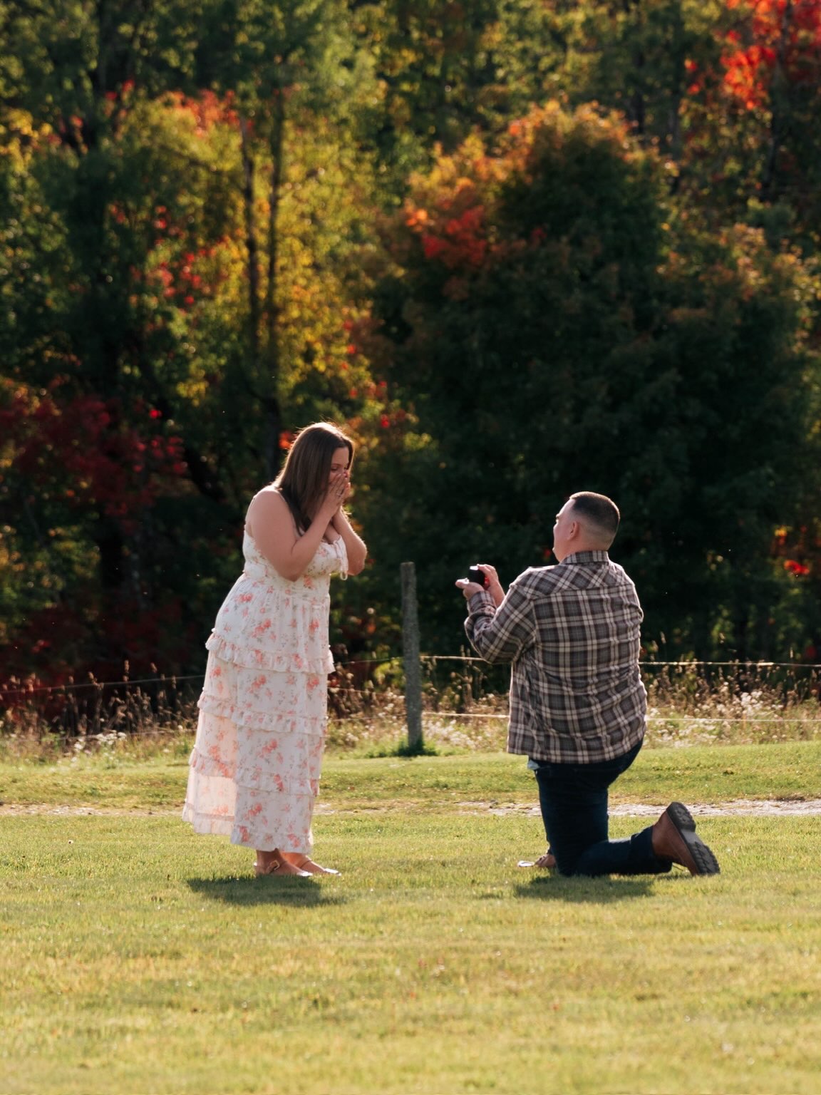 John getting down on one knee to propose to Erica in an autumn garden